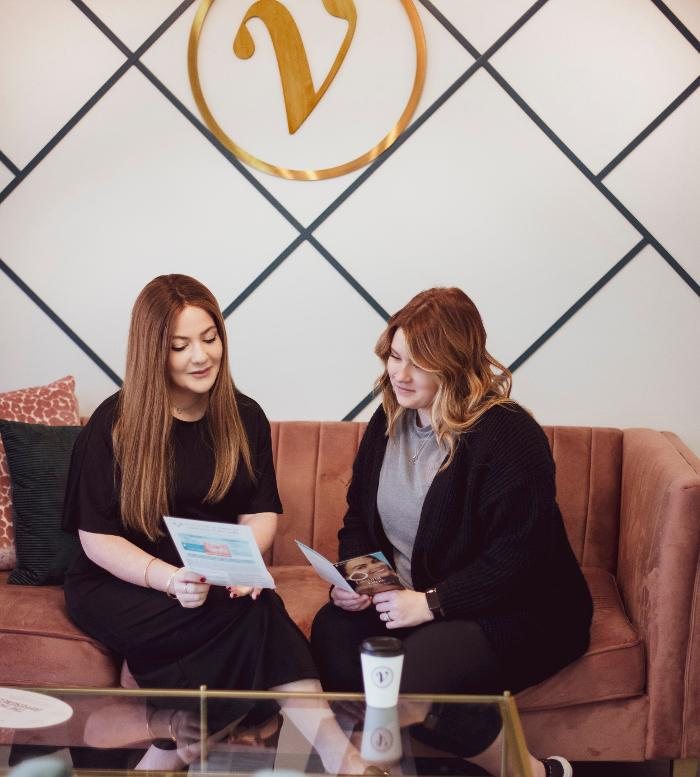 Two women reviewing a treatment plan on the couch at Viva, beneath the gold V